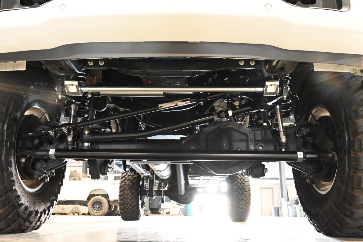 Front axle, track bar and control arms of a lifted truck on the Pro One shop floor
